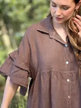 Vestido camisero blanco de lino italiano, con cuello camisero, cierre frontal con botones, mangas cortas con doble volado y bolsillos laterales.