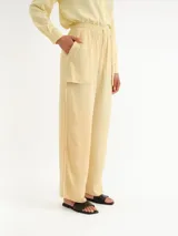 Pantalón de corte ancho, color amarillo claro, con cintura elástica fruncida y cordón ajustable. Cuenta con bolsillos frontales aplicados y dobladillo ancho en los tobillos.