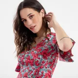 Vestido corto con estampado floral en tonos rojos y celestes, con escote en V y mangas cortas acampanadas.