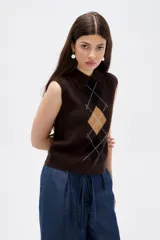 Chaleco de punto sin mangas con cuello polo, diseño de rombos estilo argyle en tonos marrón, negro y beige.