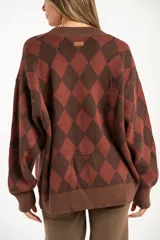 Cardigan de punto con diseño de rombos en tonos marrón y terracota, cuello en V, cierre frontal con botones y mangas largas con puños acanalados.