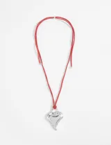 Collar de cordón rojo con dije metálico plateado en forma de corazón con textura.