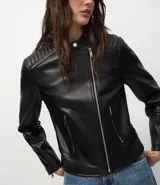 Campera biker de poliuretano color verde oliva, con cierre frontal asimétrico, bolsillos laterales con cremallera y detalle capitoneado en los hombros.