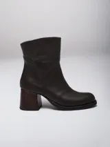 Botas de caña baja en cuero color marrón oscuro, con taco cuadrado y punta redondeada. Presentan un diseño tipo western con estribo desmontable que incluye una hebilla metálica decorativa.