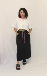 Falda larga de estilo deportivo confeccionada en tejido de algodón y poliéster. Presenta cintura elástica con cordón de ajuste en color fucsia, bolsillos laterales y un aplique decorativo de acrílico en la parte frontal.