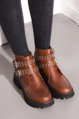 Bota corta color marrón óxido, con suela track negra, doble correa con hebillas plateadas y detalle de ojales.