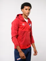 Campera deportiva Umbro del Club Nacional de Football, modelo Summit. Presenta un diseño con bloques de color en azul, rojo y blanco, con capucha, cierre frontal y bolsillos laterales con cierre. Incluye el logo de la marca y el escudo del club en el pecho.