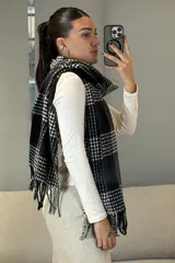 Bufanda rectangular con diseño de cuadros escoceses en blanco y negro, con flecos en los extremos.