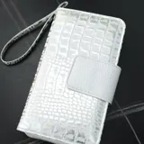 Billetera blanca con textura croco, cierre con broche y correa de mano.