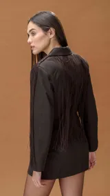 Blazer tipo vestido color chocolate, de corte cruzado con doble botonadura frontal. Presenta solapas clásicas y flecos largos decorativos en los hombros y mangas que aportan movimiento.