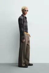 Camisa de corte relajado confeccionada en tejido fluido con mezcla de viscosa. Presenta diseño de cuadros en tonos grises y azul oscuro, cuello solapa, manga larga con puños abotonados y cierre frontal de botones.