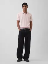 Buzo tipo polo de manga corta en tejido de punto color negro, con cuello y cierre frontal parcial con botones.