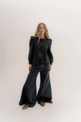 Jean de tiro medio color negro, con corte ajustado en la cintura y piernas muy amplias con cortes curvos en el ruedo. Incluye bolsillos delanteros y bolsillos plaque en la espalda.