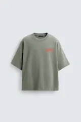 Sudadera de corte boxy fit, color verde oliva con efecto lavado. Presenta cuello redondo, manga corta terminada en rib y textos estampados a contraste en color rojo en el pecho.