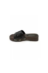 Sandalia tipo zueco Paddock de color negro, con plataforma baja de aspecto amaderado y tiras entrelazadas en el empeine. Presenta detalles de tachas metálicas doradas en los laterales y plantilla acolchada.