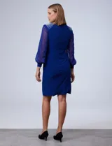 Vestido de fiesta azul eléctrico, marca RM Richards, confeccionado en seda fría. Presenta escote en V cruzado, drapeado lateral, mangas largas de gasa y apliques de strass en los hombros.