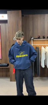 Hoodie azul marino de corte oversize con capucha y bolsillo frontal tipo canguro. Presenta un estampado gráfico en el pecho con el texto 'Ittaistars' en color amarillo.