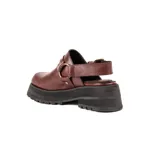 Zueco de cuero vacuno color bordó, con diseño de punta cuadrada y tira trasera ajustable con hebilla metálica. Presenta detalles de herrajes en tono oro viejo y una plataforma de goma negra con suela dentada.