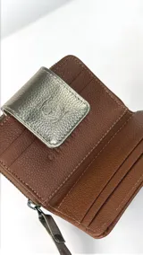 Billetera compacta de cuero texturizado color marrón, con solapa frontal en cuero metalizado dorado que presenta un grabado de búho. Incluye cierre lateral y correa de muñeca a juego.