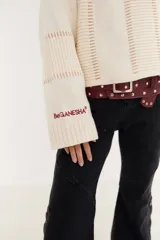 Sweater de punto color beige, con diseño de textura acanalada en mangas y espalda, cuello polo en color bordó y parche decorativo en la parte superior de la espalda.