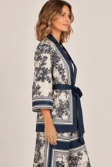 Kimono de seda liviano con estampa estilo toile de Jouy en tonos marrones y beige, con detalles de guardas geométricas, mangas tres cuartos anchas, bolsillos laterales y lazo para ajustar en la cintura.