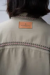 Campera de jean color beige con bordados florales en tonos rosa, verde y amarillo.