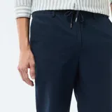 Pantalón chino azul marino, de corte regular, confeccionado con mezcla de lino y algodón. Cuenta con bolsillos laterales y traseros, y cierre frontal con botón y cremallera.
