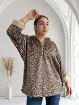 Buzo con capucha color marrón con estampado animal print de leopardo y cierre frontal con cremallera. Interior y puños de piel sintética color crema.