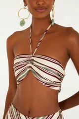 Top de rayas horizontales en tonos crudo, borgoña y verde, con diseño sin tirantes, detalle torcido en el busto y cierre con cordón ajustable.