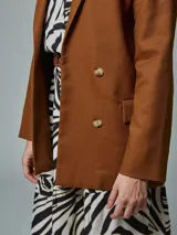 Blazer recto color crudo, de lino, con solapas de muesca, cierre cruzado con doble botonadura, mangas largas y bolsillos con solapa.