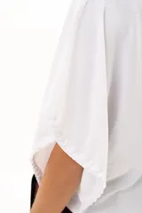 Blusa blanca de corte holgado y diseño minimalista, con mangas cortas tipo murciélago que presentan un detalle de fruncido lateral con cordón ajustable.