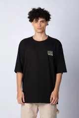 Remera blanca de corte oversize con mangas cortas y cuello redondo. Estampado pequeño en el frente con letras verdes.