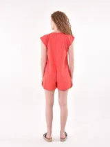 Monoprenda (romper) de color rojo, sin mangas, con cuello redondo y cierre frontal de botones. Presenta bolsillos delanteros a la altura de la cadera y un corte holgado.