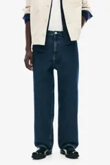 Jean de corte baggy confeccionado en denim de algodón rígido, con diseño de cinco bolsillos, tiro bajo y piernas amplias de silueta redondeada.
