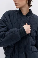 Cazadora tipo bomber de color negro con diseño acolchado de rombos, cuello, puños y ruedo acanalados, cierre frontal y bolsillos laterales.