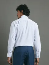 Camisa de vestir de manga larga con cuello clásico y cierre frontal de botones. Presenta un estampado de micro puntos en tonos blanco y azul.