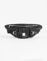 Riñonera negra de cuero vegano con múltiples bolsillos frontales con broches y cierre principal. Presenta una hebilla rectangular metálica en el centro y detalles de correas ajustables con argollas en forma de D.