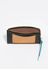 Billetera de cuero vacuno en color negro con bolsillo exterior en color naranja y tirador de cierre en color turquesa. Cuenta con logo de la marca estampado en dorado.