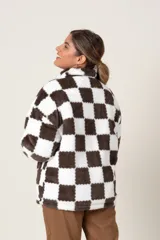 Campera de poliéster símil piel, con estampado a cuadros blancos y negros, cierre frontal y bolsillos laterales.