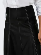 Pollera midi de tiro medio confeccionada en cuero sintético negro, con costuras a la vista en color blanco y diseño acampanado.