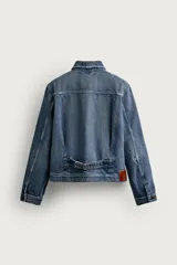 Campera de denim de algodón en color azul, con lavado efecto desgastado, cuello solapa y cierre frontal de botonadura metálica. Presenta bolsillos con solapa en el pecho, mangas largas con puños abotonados y trabilla ajustable en la cintura posterior.