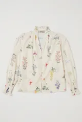 Camisa de manga larga color arena con delicado estampado floreado, cuello mao con volados, escote en V con botones frontales y puños fruncidos elastizados.