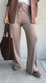 Pantalón de tejido de punto acanalado en color beige, con corte recto y holgado. Presenta cintura elástica con cordón ajustable y terminaciones simples.