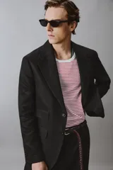 Blazer de corte regular confeccionado en lino, con solapas de muesca, cierre frontal de botones y múltiples bolsillos con solapa en la parte frontal. Presenta un diseño estructurado con abertura en la espalda y forro parcial.
