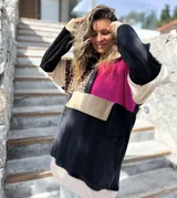 Buzo de estilo canguro con diseño color block que combina paneles en negro, fucsia, beige y un estampado de leopardo. Presenta cuello con cierre de botones a presión y un bolsillo frontal tipo canguro.