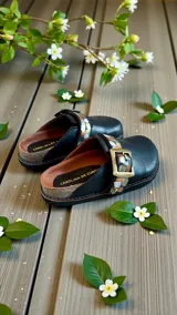 Sandalias de cuero color negro, estilo zueco, con tira ajustable mediante hebilla metálica grande y detalles pintados a mano en tonos dorados, plateados y cobre.