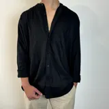 Camisa de manga larga en tejido de lino, color blanco, con cuello mao y cierre frontal de botones. Presenta un corte oversize y mangas con puños doblados.