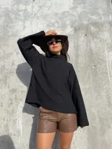 Polerón negro de calce holgado con cuello alto y mangas amplias, confeccionado en tela suave y abrigada.