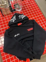 Hoodie negro de corte oversize con capucha, confeccionado en algodón. Presenta un estampado gráfico en color rojo en la espalda con la leyenda 'ITTAI STARS THE STAR BRAND DESIGNED IN VENICE' y un detalle bordado en blanco en la parte posterior de la capucha.