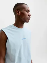 Musculosa celeste de corte holgado y cuello redondo, confeccionada en algodón. Presenta un pequeño estampado gráfico frontal con texto.
